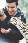 Lächelnder junger Mann füttert Leoparden im Zoo — Stockfoto