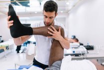 Il fisioterapista che tratta un uomo usando attrezzature per la radioterapia — Foto stock