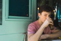 Jeune homme confiant assis avec un verre de bière à table — Photo de stock