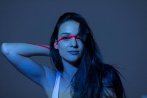 Giovane donna attraente con linea rossa sul viso e braccio guardando su sfondo scuro — Foto stock