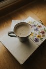 Cup of tasty warm drink placed on a book on table. — Stock Photo
