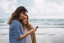 Due amici sorridenti che si fanno selfie in riva al mare — Foto stock