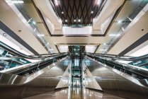 Duas escadas rolantes localizadas no salão iluminado do shopping moderno, Cingapura — Fotografia de Stock