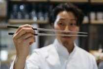 Primer plano del chef japonés sosteniendo palillos - foto de stock