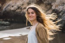 Portrait of girl with long brown hair standing on beach — Stock Photo