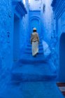 Donna che cammina sulle scale sulla strada blu tinta, Marocco — Foto stock
