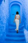 Задний вид женщины, идущей по синей лестнице по улице в Марокко — стоковое фото
