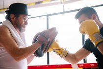 Vue latérale du boxeur homme gants de boxe de boxe dans la salle de gym. — Photo de stock