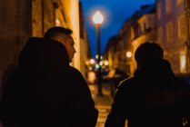 Two men walking together on illuminated street at night — Stock Photo