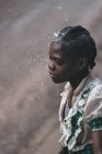 CAMERÚN - ÁFRICA - 5 DE ABRIL DE 2018: Niña étnica parada bajo gotas de agua - foto de stock