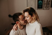 Glücklicher Mann und Frau, die zu Hause zusammen sitzen und sich umarmen — Stockfoto