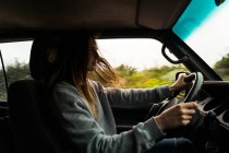 Frau mit langen braunen Haaren fährt Auto in der Natur — Stockfoto
