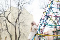 Fröhliches Mädchen klettert auf Spielplatz an Seilen — Stockfoto