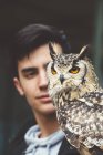 Homme regardant hibou assis sur la main — Photo de stock