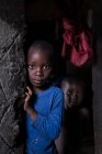 ANGOLA - ÁFRICA - 5 de abril de 2018 - Pequeños niños negros en casa gruñona mirando a la cámara - foto de stock