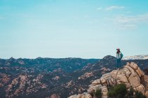 Frau steht auf Felsen in den Bergen und blickt auf die Aussicht — Stockfoto