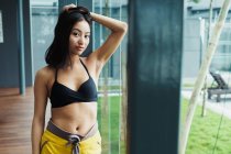 Ziemlich asiatische Frau in Sportbekleidung berühren Haare und Blick auf Kamera — Stockfoto