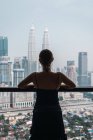 Женщина смотрит на небоскребы, стоя у окна — стоковое фото