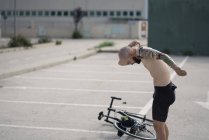 Shirtless handicapped sportsman standing near bicycle — Stock Photo