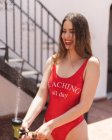 Skinny jeune femme en maillot de bain rouge s'amuser dans la cour avec tuyau d'eau pulvérisation en plein soleil — Photo de stock