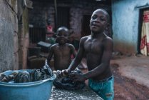 КАМЕРУН - Африка - 5 апреля 2018 года: африканские мальчики стоят на улице и стирают одежду — стоковое фото