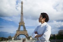 Japanese chef with arms crossed standing in front of Eiffel Tower in Paris — Stock Photo