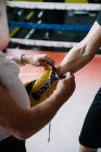 Erwachsenentrainer bindet Boxerhandschuh an die Hand des Sportlers im Ring. — Stockfoto