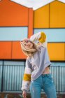 Продумана жінка з закритими очима стоїть на тлі барвистих будинків — стокове фото