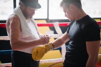 Vue latérale de l'homme adulte avec boxeur d'entraînement au cigare dans la salle de gym. — Photo de stock