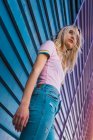 Блондинка, опирающаяся на голубую стену на улице — стоковое фото