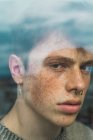 Portrait of Sensual young man with freckles behind window — Stock Photo