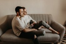 Romantisches Paar sitzt auf der Couch und entspannt mit Gitarre zu Hause zusammen — Stockfoto