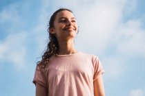 Дівчина-підліток стоїть перед блакитним небом з хмарами — стокове фото