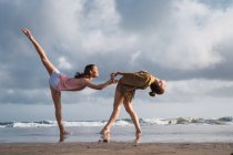 Жінки-друзі роблять вправи на пляжі під хмарним небом — стокове фото