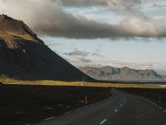 Perspective view to empty road in green picturesque mountains in cloudy day. — Stock Photo