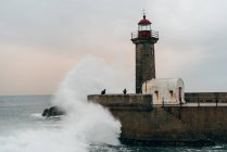 Torre beacon no cais no oceano ondulado, Porto, Portugal — Fotografia de Stock