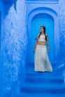 Woman wearing white top and long skirt standing on blue dyed street, Morocco — Stock Photo