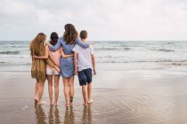 Woman and teenagers hugging together on seashore — Stock Photo
