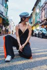 Junge asiatische Frau sitzt auf Knien auf der Straße in der Stadt und schaut weg — Stockfoto