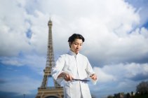 Japanese chef with knives standing in front of Eiffel Tower in Paris — Stock Photo