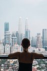 Woman standing at home and looking thorough window at skyscrapers — Stock Photo