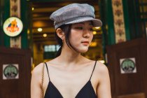 Portrait of young Asian woman wearing cap in front of building — Stock Photo
