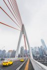 Modern suspension bridge construction with cars driving on background of metropolis of Chongqing, China — Stock Photo