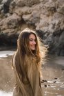Портрет девушки с длинными каштановыми волосами, стоящей на пляже — стоковое фото