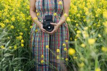 Mulher em vestido colorido segurando dispositivo de foto na natureza — Fotografia de Stock