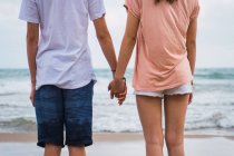 Teenager friends standing and holding hands on beach — Stock Photo