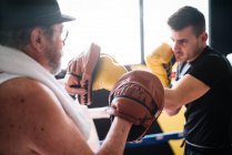 Вид сбоку боксёра на перчатки тренера в тренажерном зале. — стоковое фото