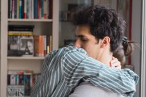 Joven hombre y mujer en pijama abrazando con los ojos cerrados en casa - foto de stock