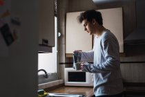 Homem no pijama derramando café na xícara na cozinha — Fotografia de Stock