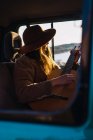 Femme avec guitare assise en voiture dans la nature — Photo de stock